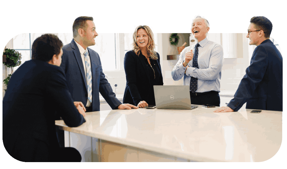Five professionals laughing around a white countertop with laptop in a Racine, WI office